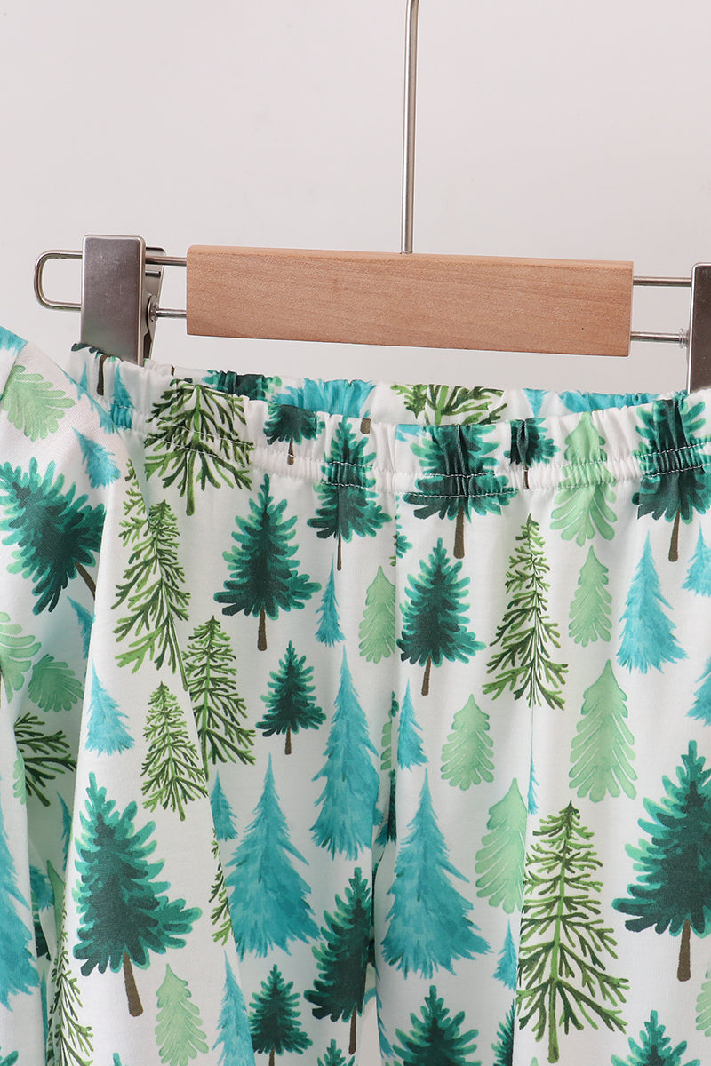 Pajama pants with tree pattern on a hanger against a white background