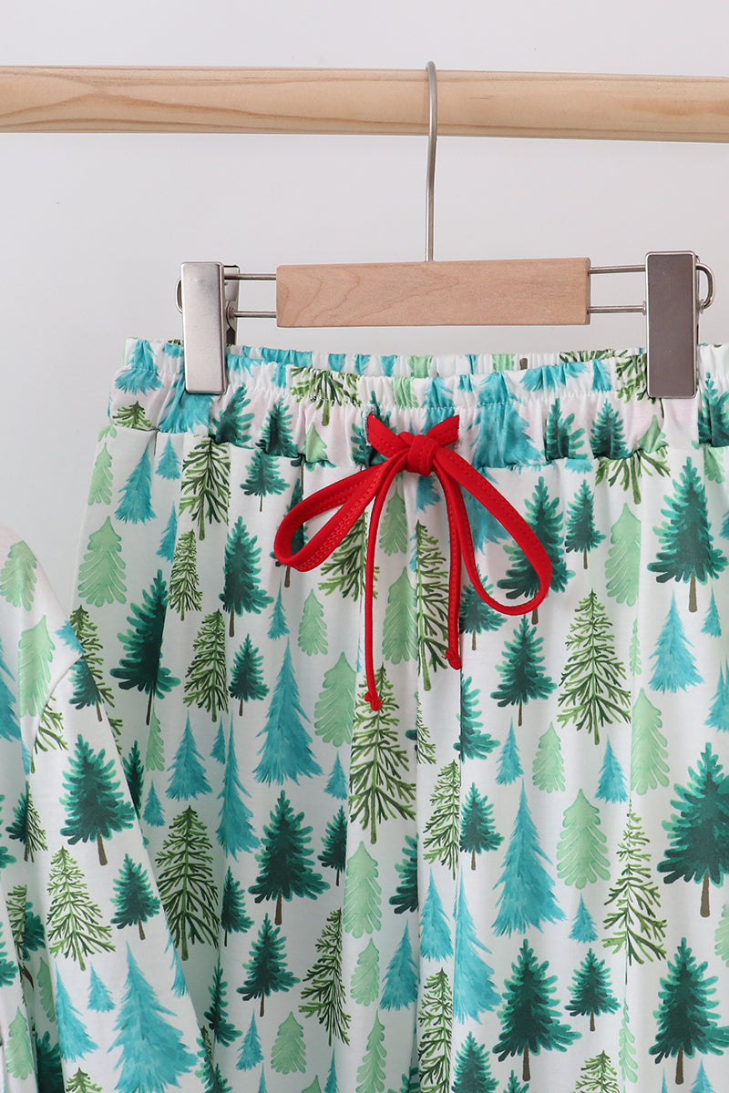 Pajama pants with tree pattern and red drawstring on a hanger against a white background