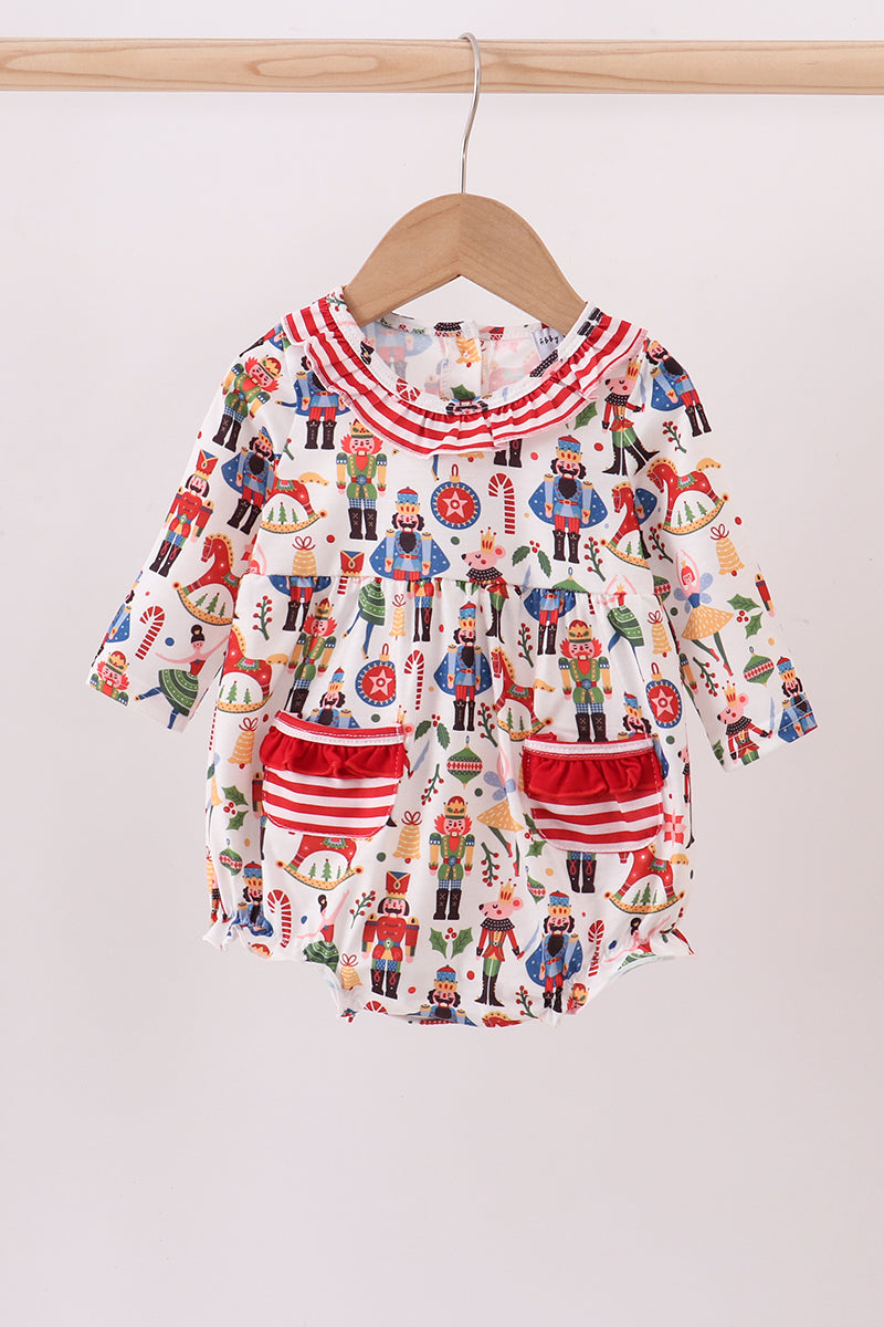 Baby romper with nutcracker pattern on a wooden hanger against a white background