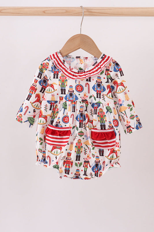 Baby romper with nutcracker pattern on a wooden hanger against a white background
