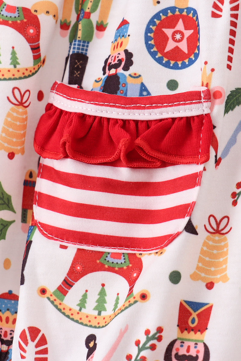 Children's outfit with red and white striped pants and a colorful top on a patterned background.