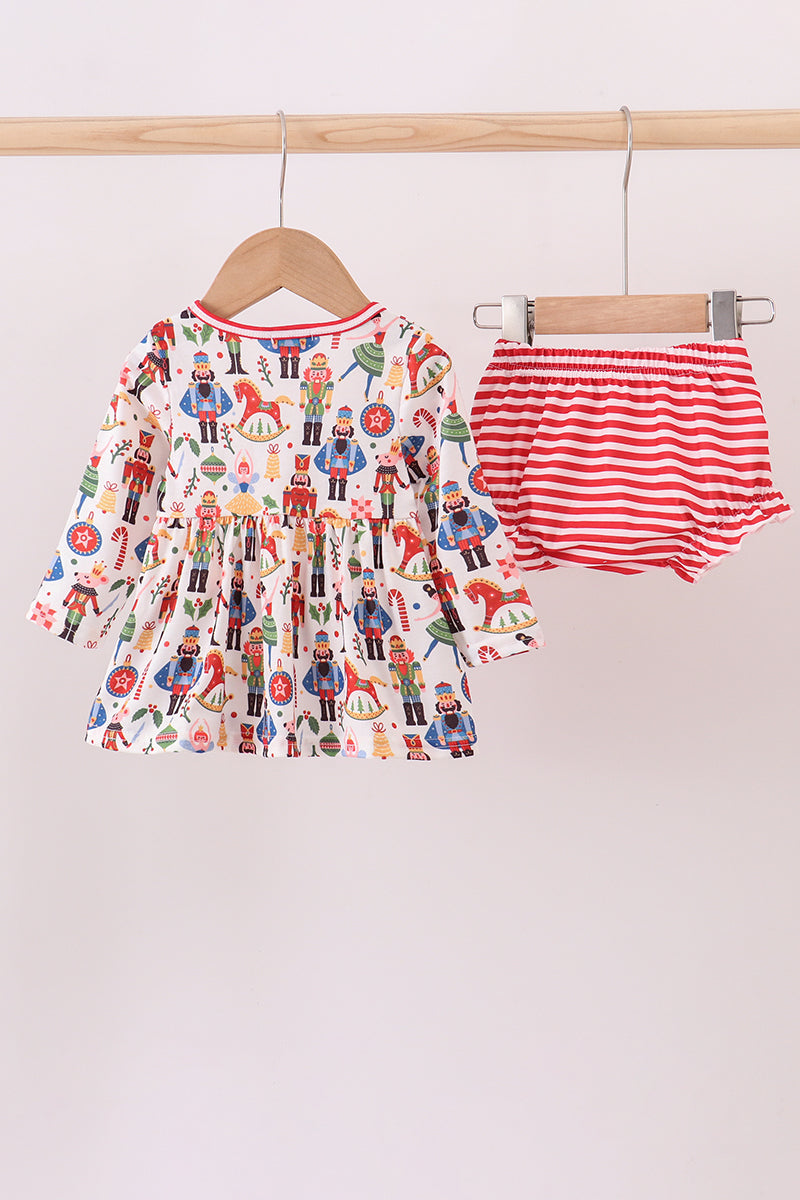 Children's outfit with dress and striped shorts on a hanger against a white background