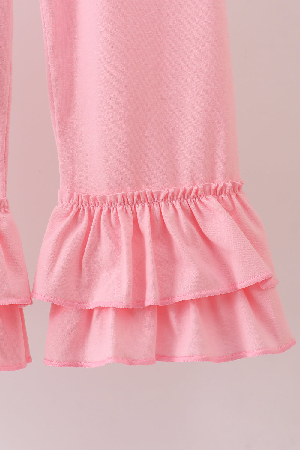 Close-up of a pink skirt with ruffled layers on a light pink background
