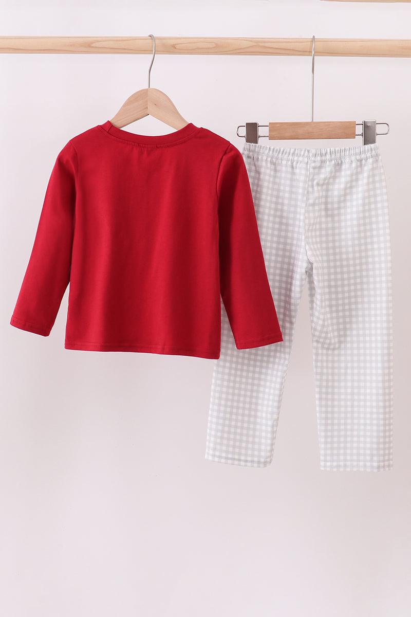 Red shirt and white checkered pants hanging on wooden hangers against a light background