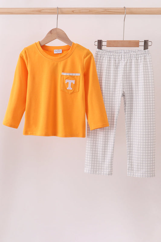 Orange long-sleeve shirt with a pocket and checkered pants on hangers against a light pink background