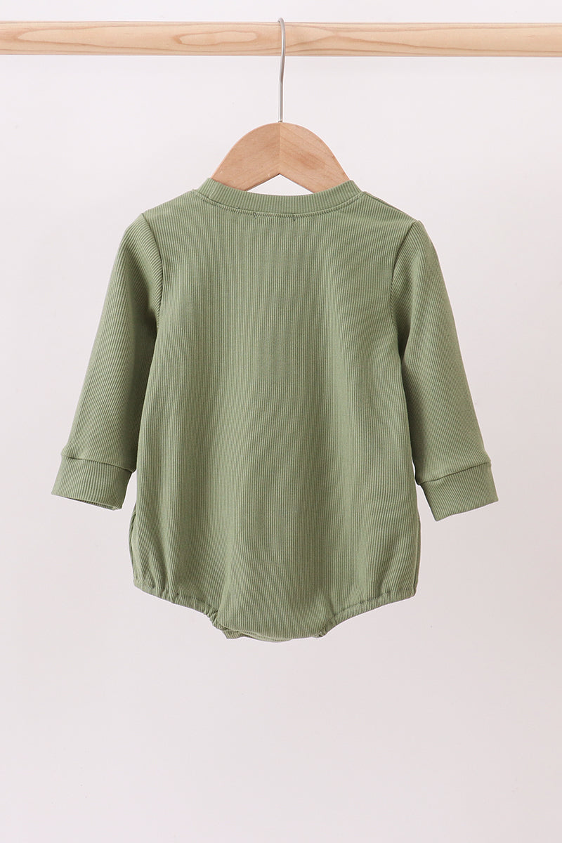 Green baby romper on a wooden hanger against a white background