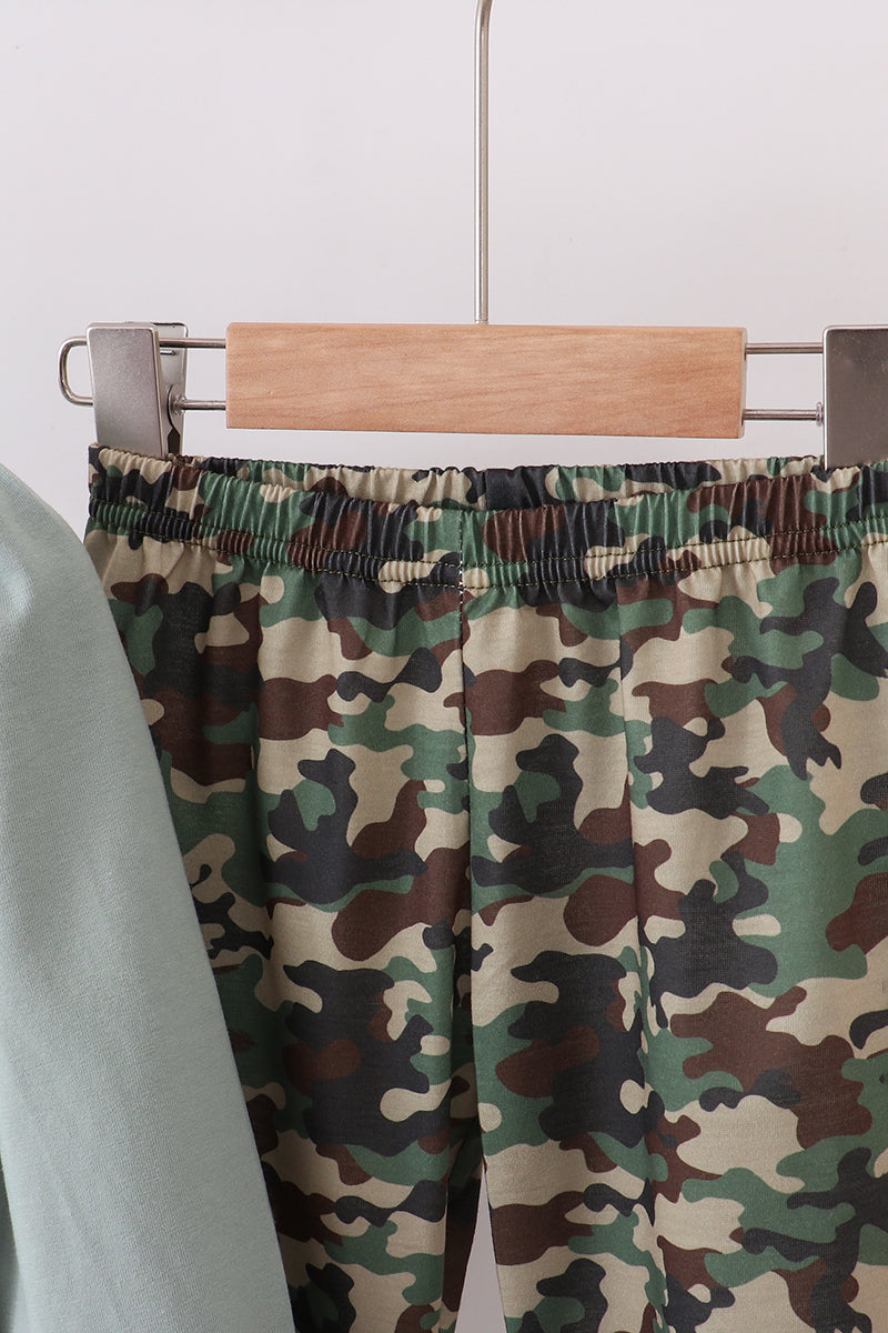 Camouflage pants on a hanger against a white background