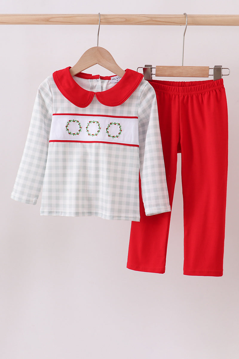 Children's outfit with checkered shirt and red pants on a hanger against a light background