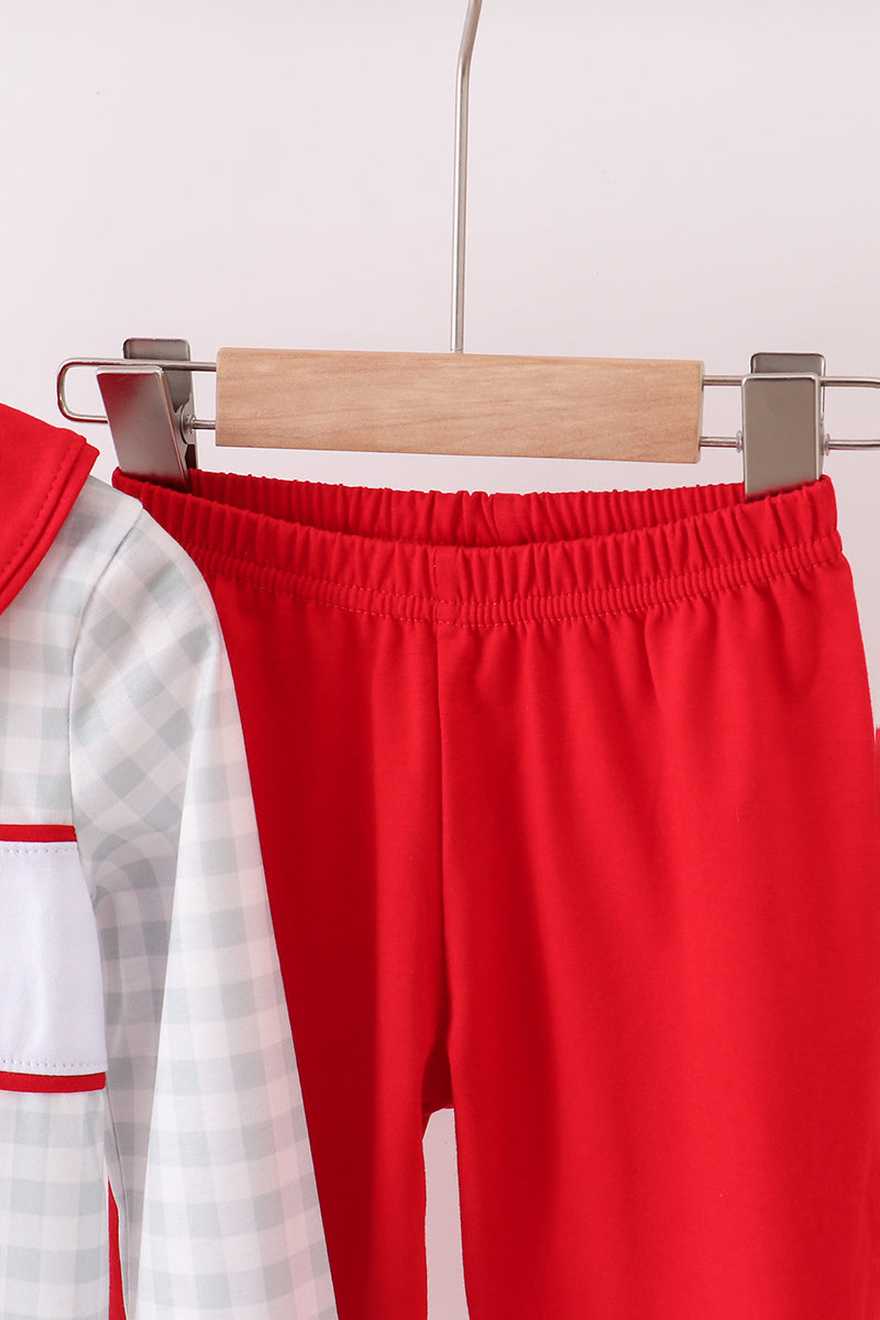 Red pants on a hanger with a white and red checkered shirt in the background