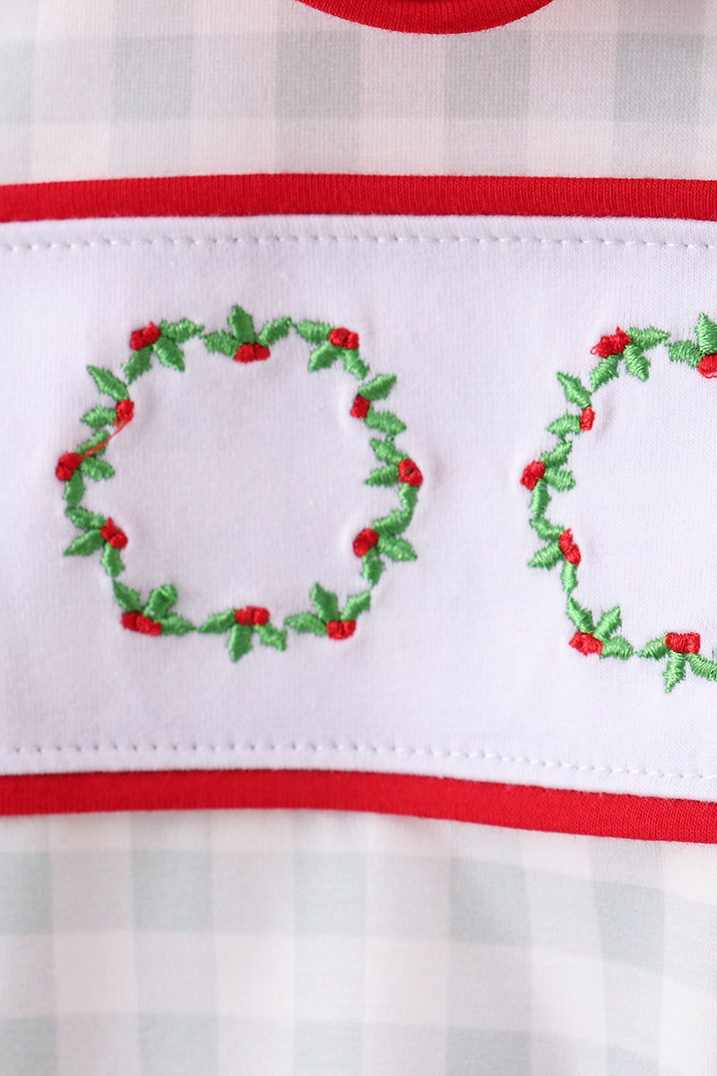 Embroidered holly wreaths on a white and red striped fabric