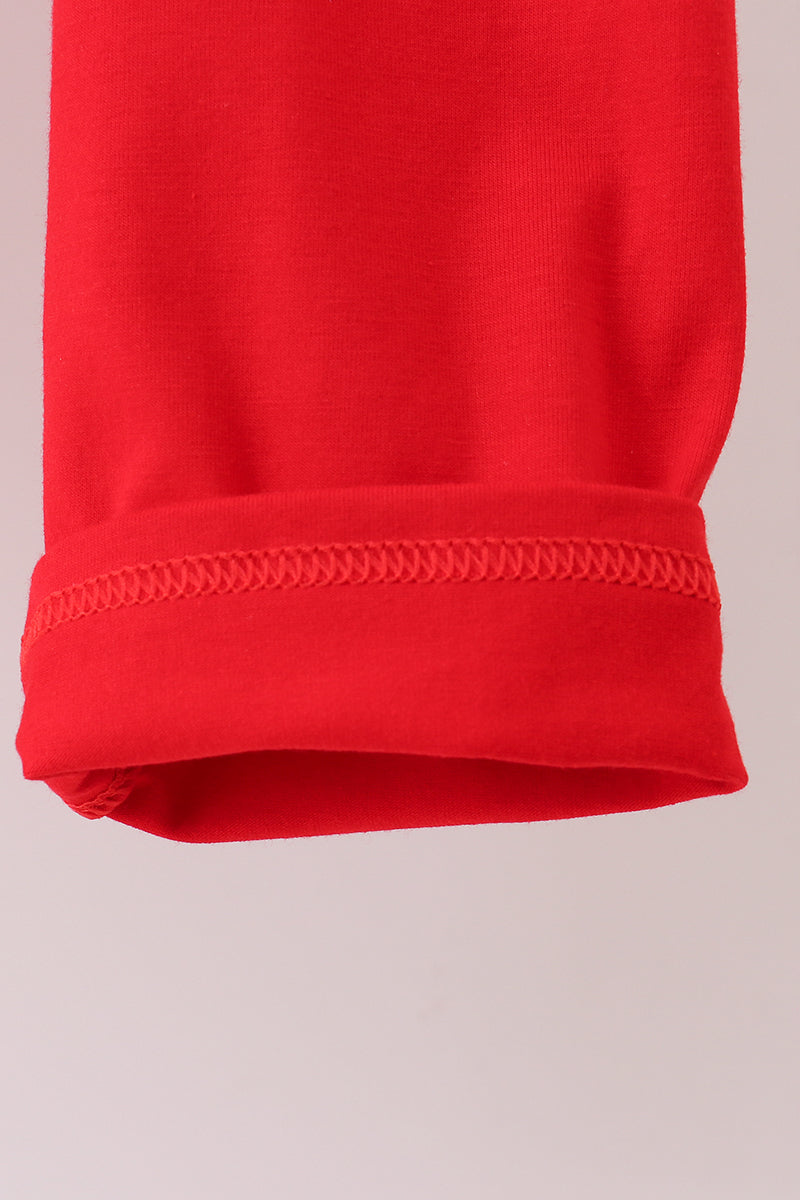 Close-up of a red fabric with a visible seam on a light pink background