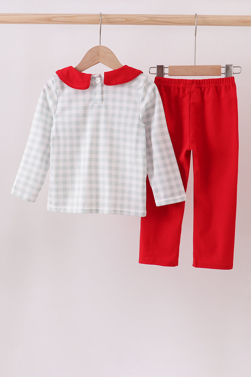 Children's outfit with white checkered shirt and red pants on hangers against a light background