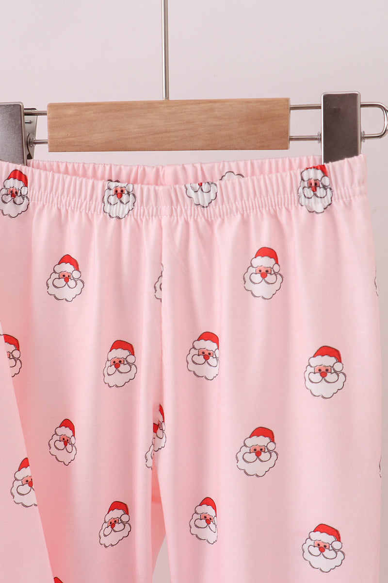 Pink pants with Santa Claus prints on a hanger against a light background
