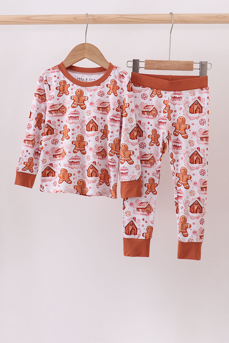 Children's pajama set with gingerbread pattern on a hanger against a white background