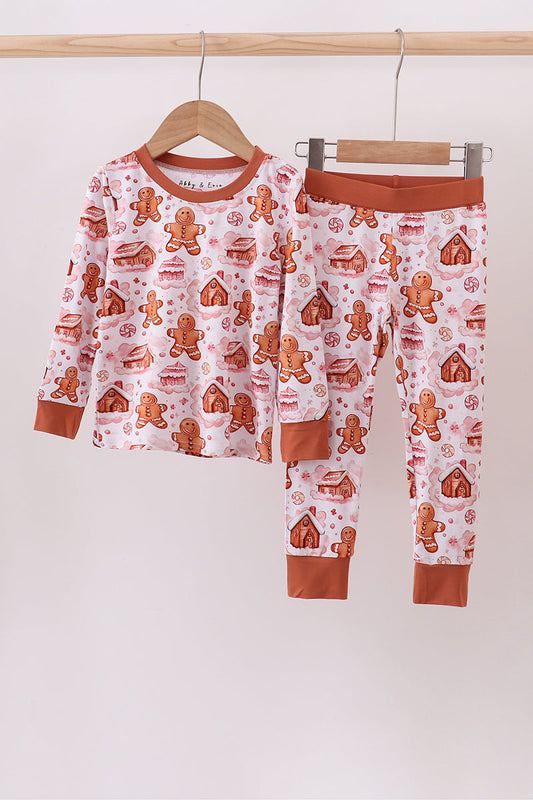 Children's pajama set with gingerbread pattern on a hanger against a white background