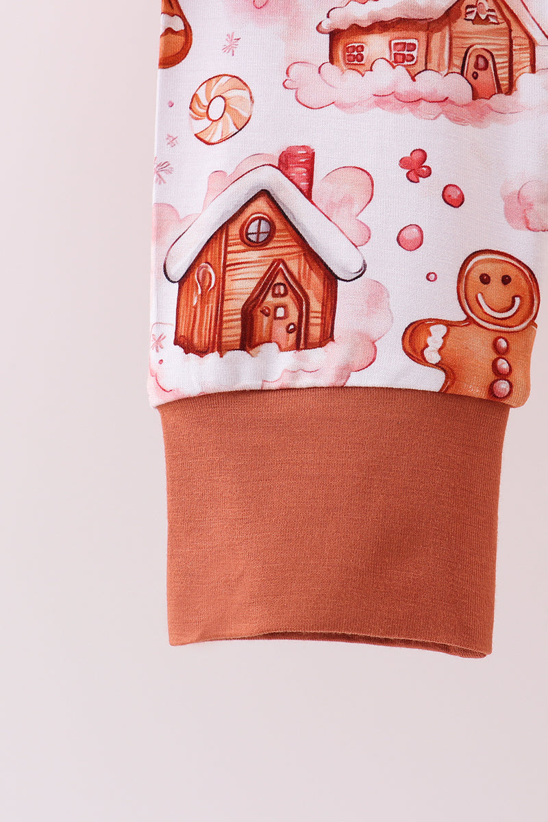 Children's outfit with gingerbread house and gingerbread man design on a light pink background