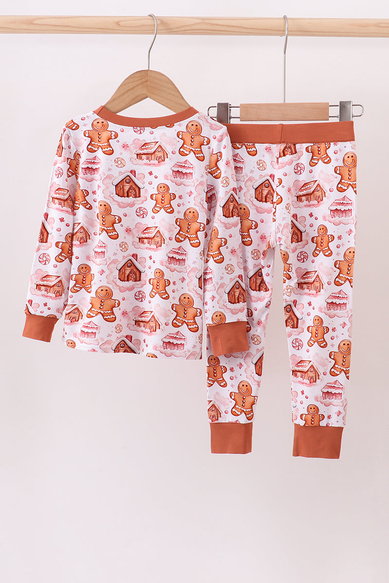 Children's pajama set with gingerbread pattern on a hanger against a white background