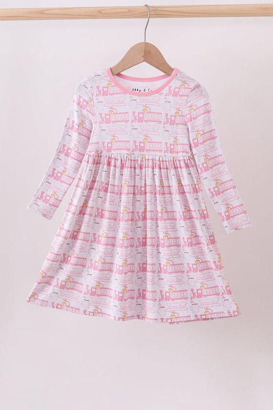 Children's dress with train pattern on a hanger against a white background