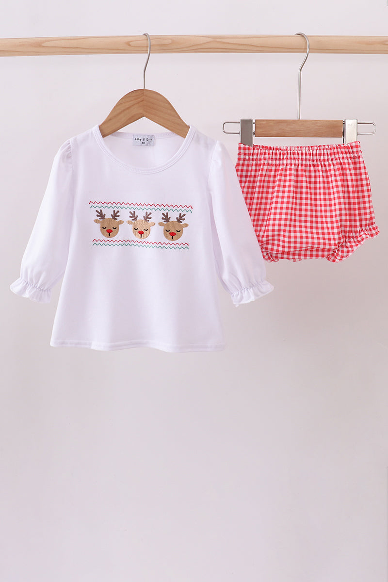 Children's outfit with white long-sleeve shirt and red checkered shorts on a wooden hanger against a white background.
