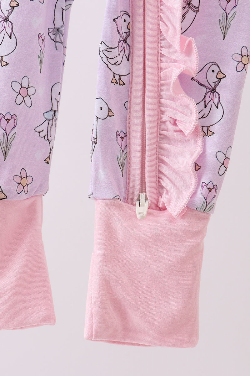 Children's outfit with pink ruffled trim and duck pattern on a light purple background