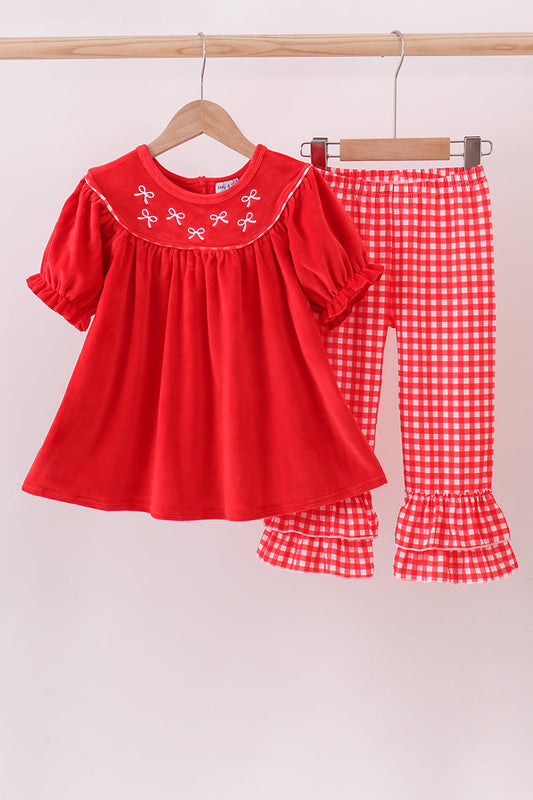 Red blouse with white embroidery and red checkered pants on a hanger against a beige background
