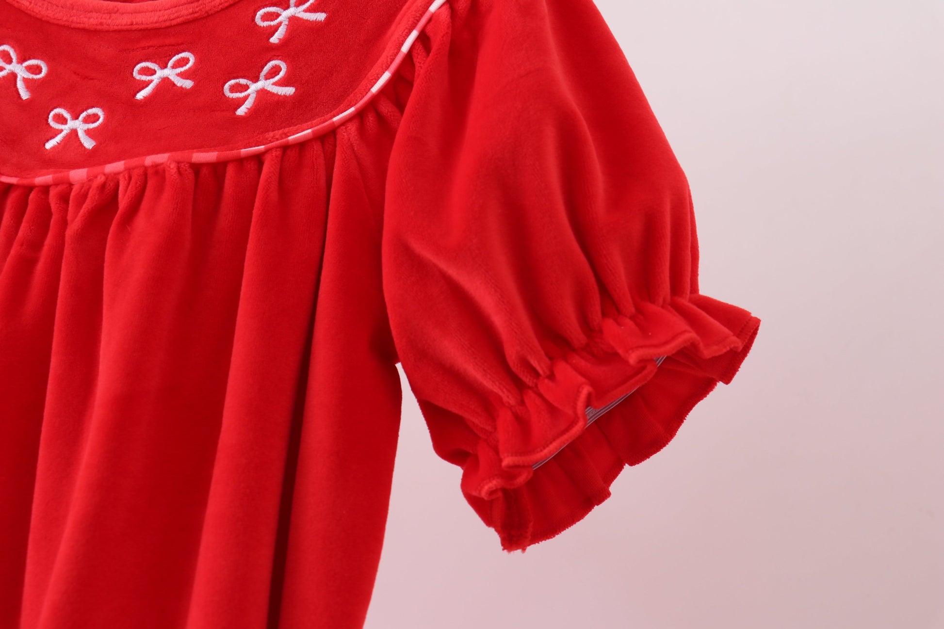 Red dress with embroidered details on a light pink background