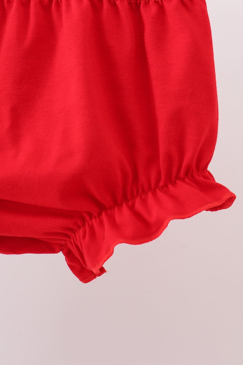 Close-up of a red fabric with gathered waistband on a light pink background