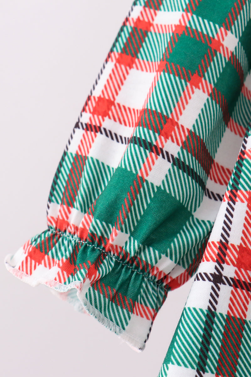 Close-up of a plaid fabric with red, green, and white colors on a light gray background.
