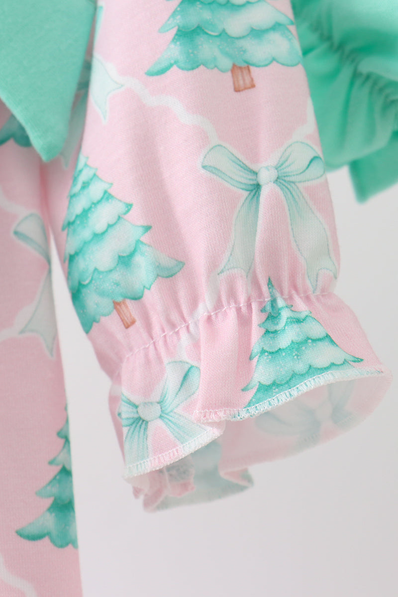Close-up of a pink dress with green tree and bow pattern on a white background