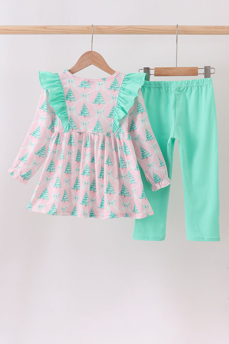Children's outfit with pink dress and green pants on a wooden hanger against a white background