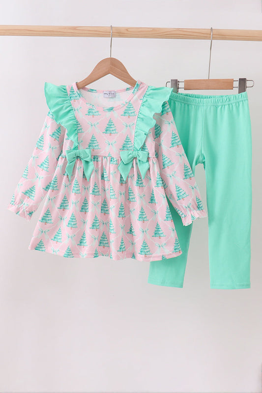 Children's outfit with pink dress and green pants on hangers against a white background