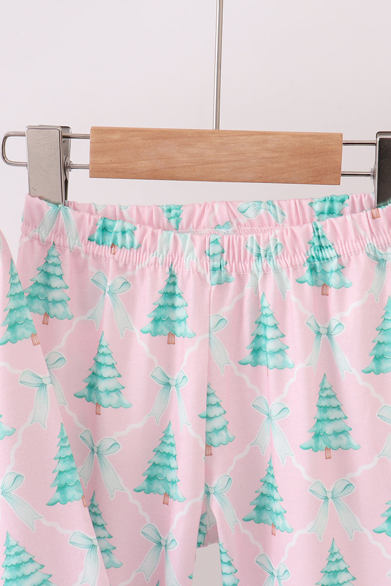 Pink shorts with green tree pattern on a hanger against a white background