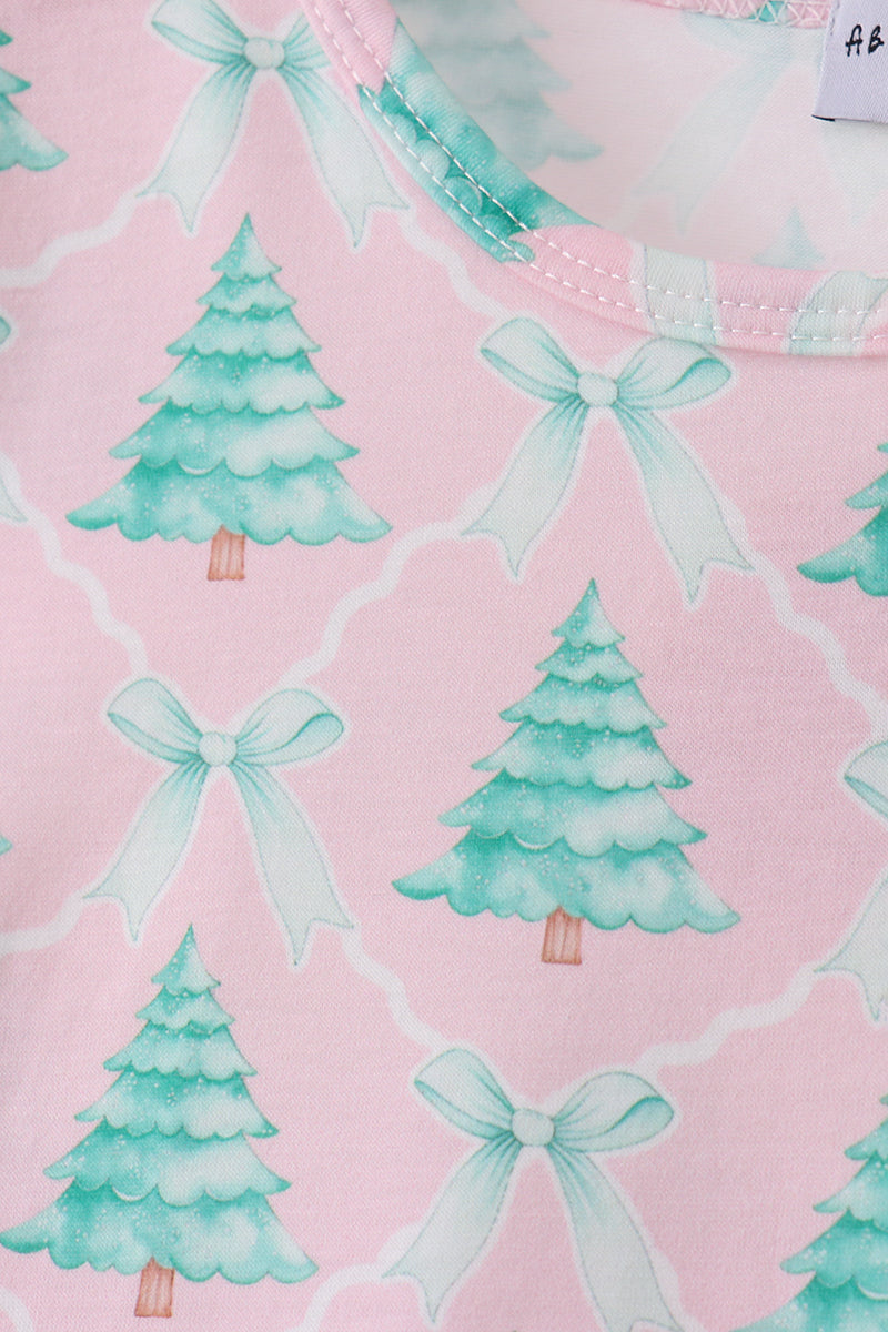 Fabric with green Christmas trees and white bows on a pink background