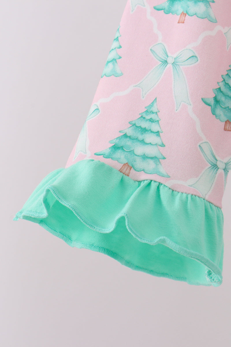 Close-up of a dress with pink background, green trees, and white bows on a light gray background
