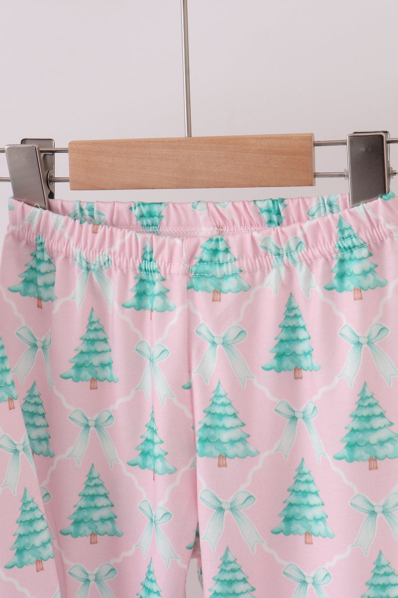 Pink fabric with green tree and bow pattern on a wooden hanger against a white background
