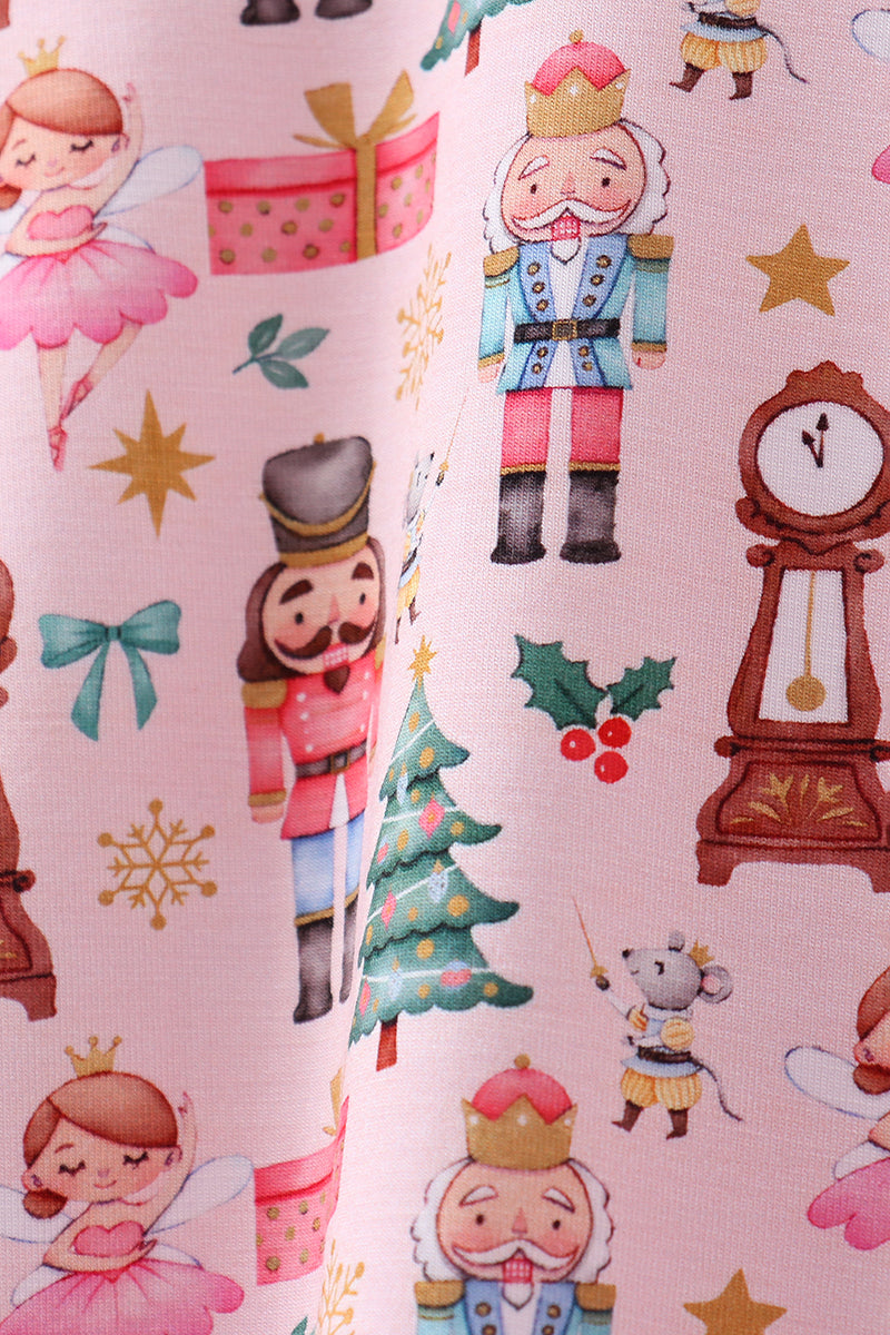 Fabric with Christmas-themed design featuring nutcrackers, fairies, and a clock on a pink background.