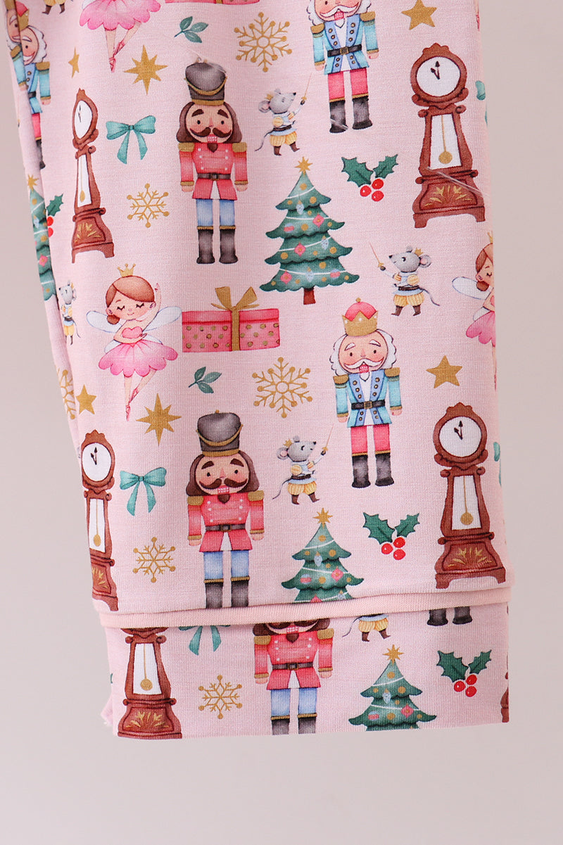 Fabric with Christmas-themed design featuring nutcrackers, trees, and presents on a pink background.