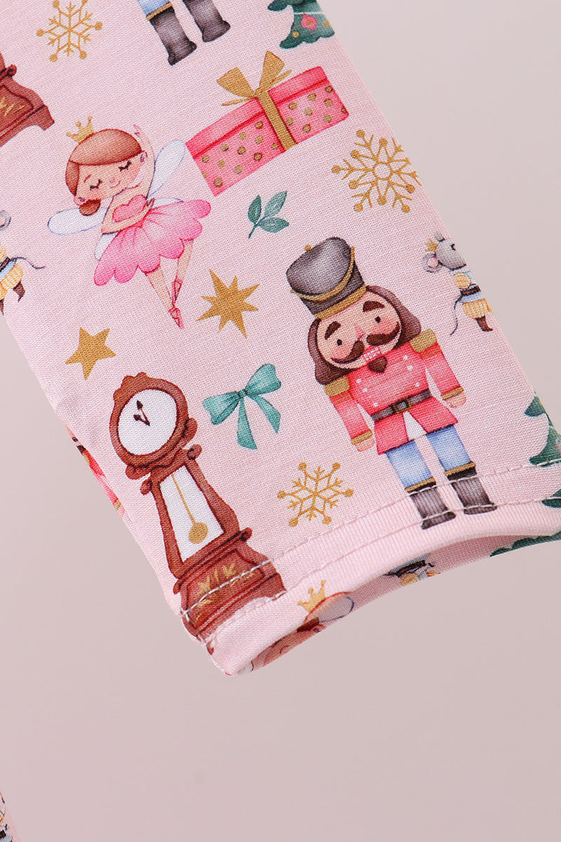 Fabric with Christmas-themed design featuring a nutcracker, clock, and presents on a pink background.