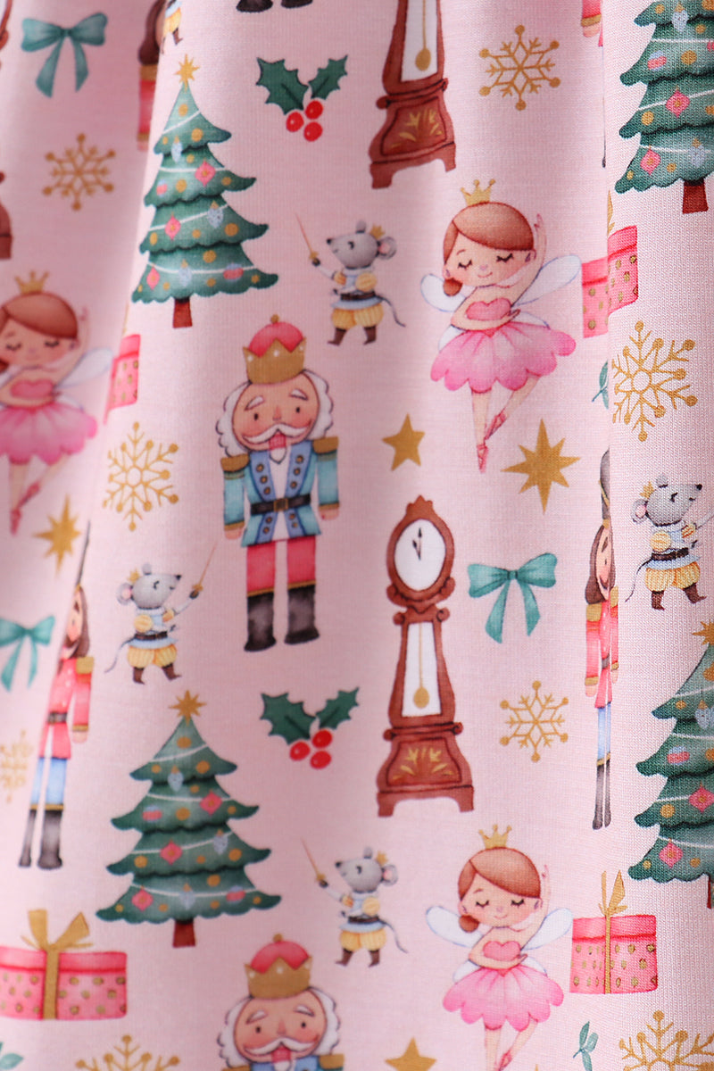 Christmas-themed fabric with nutcrackers, trees, and presents on a pink background