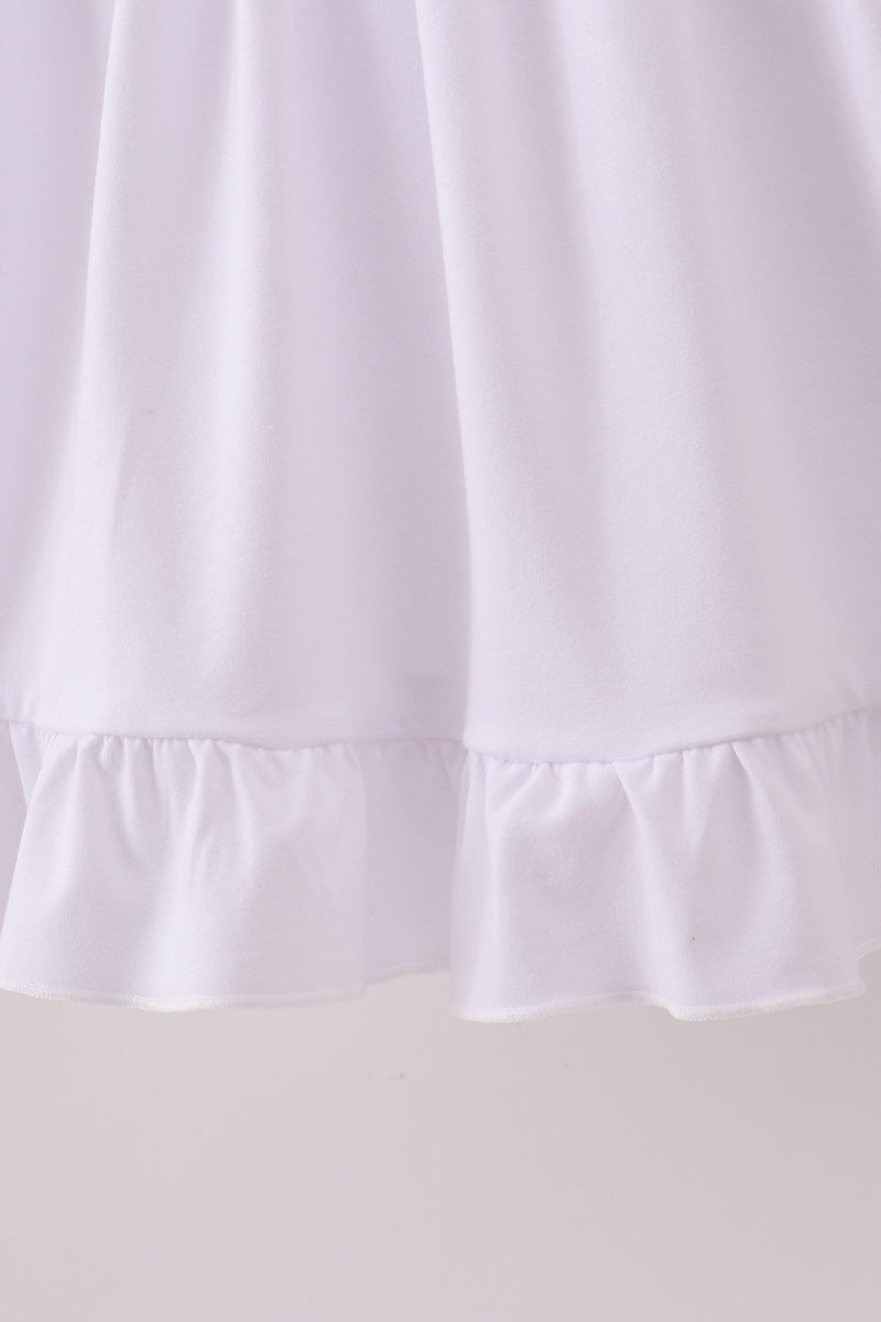 Close-up of a white dress with ruffled hem on a light gray background