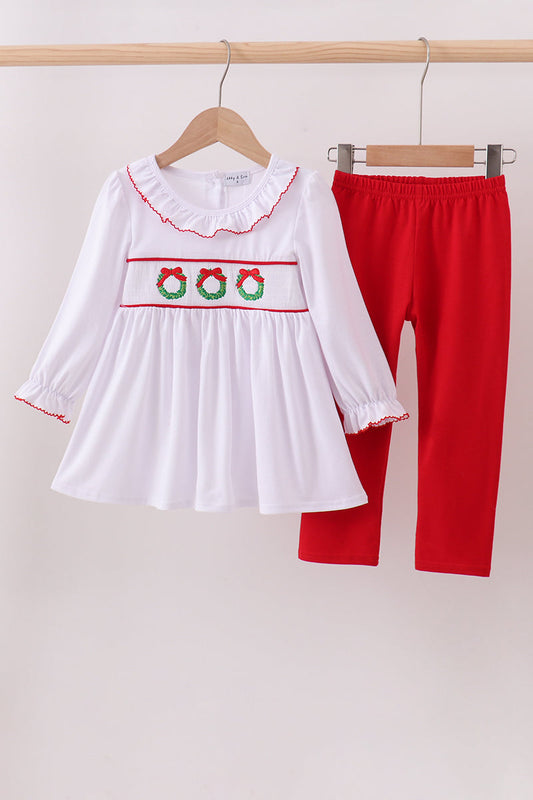 White dress with red trim and red pants on hangers against a white background