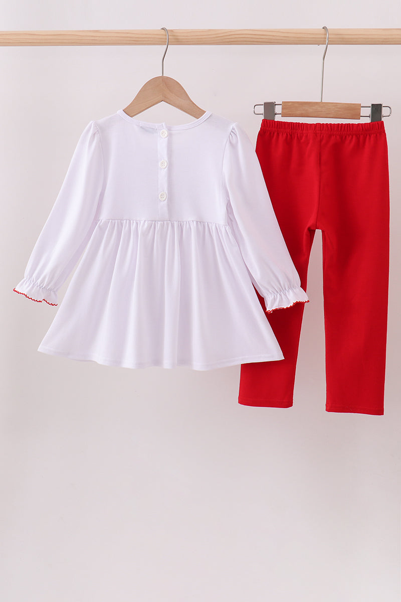 White dress and red pants hanging on a rack against a white background