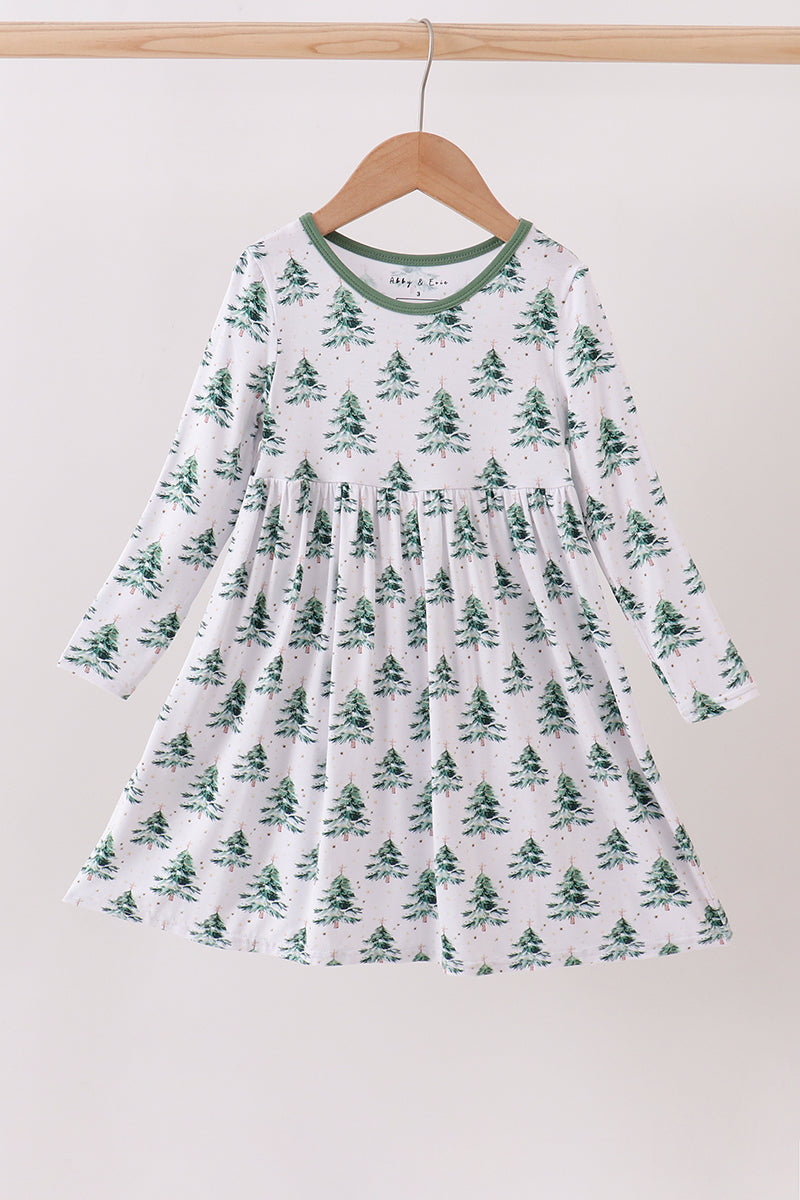 White dress with green tree pattern on a hanger against a white background