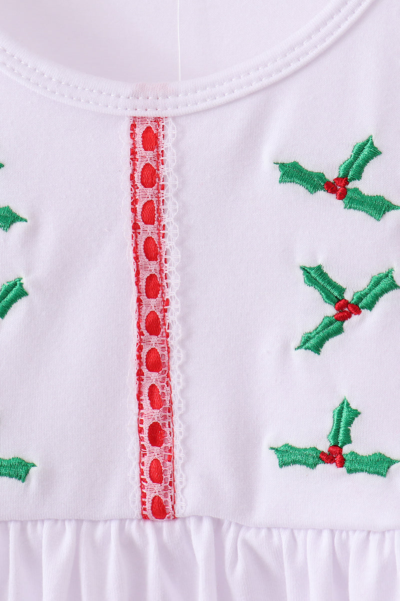 Close-up of a white garment with green holly designs and red heart details.