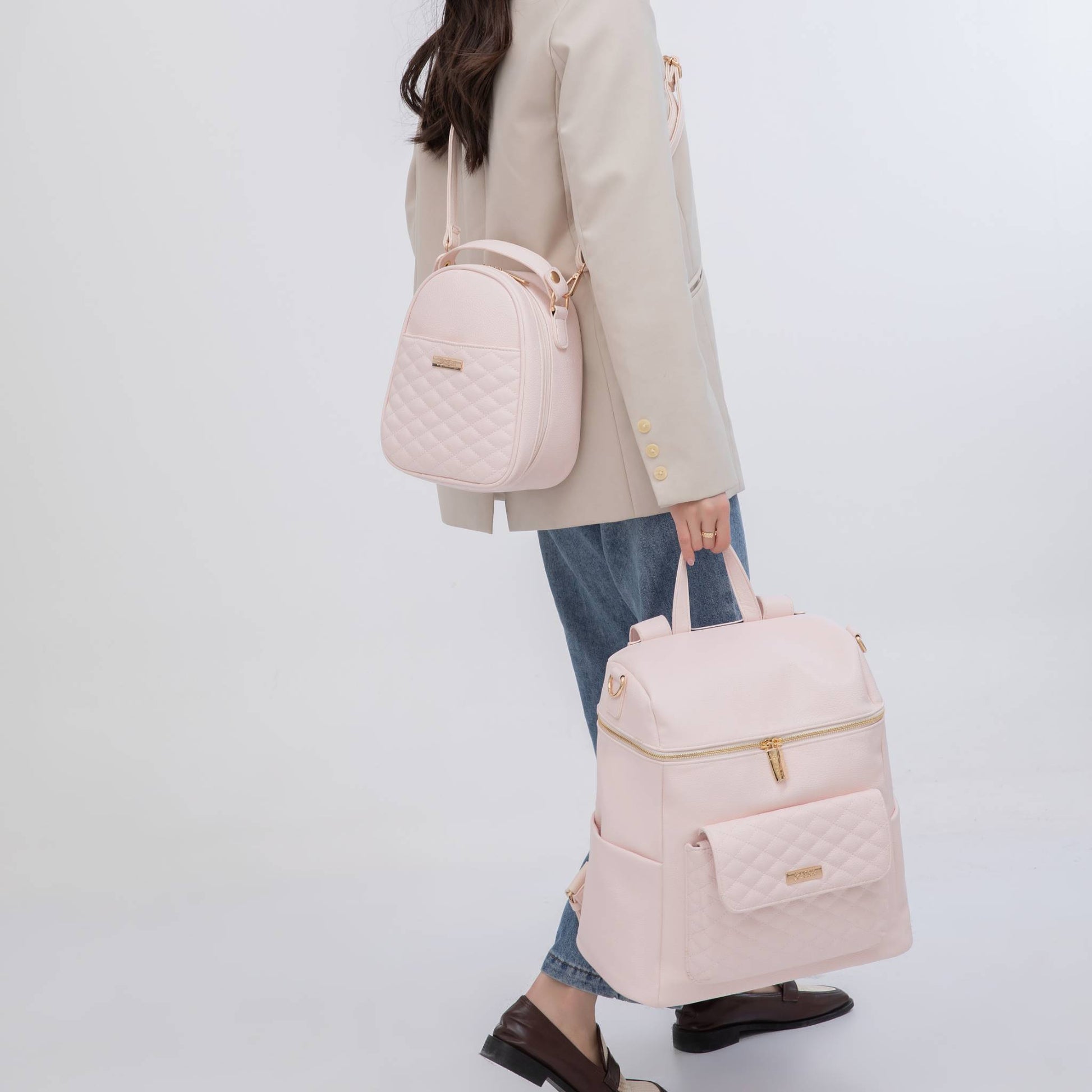 Person holding two pink backpacks against a white background