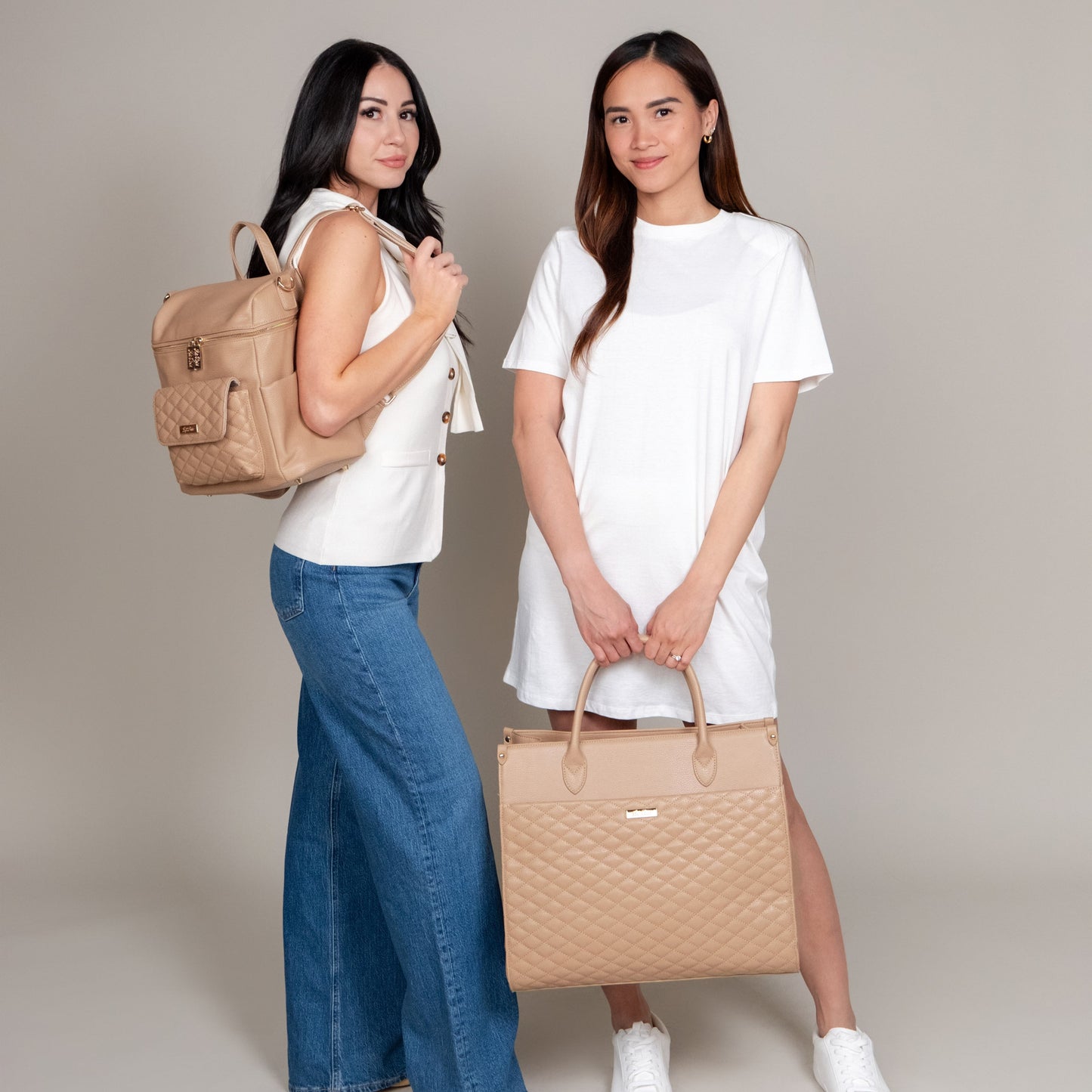 Two women holding beige handbags against a plain background