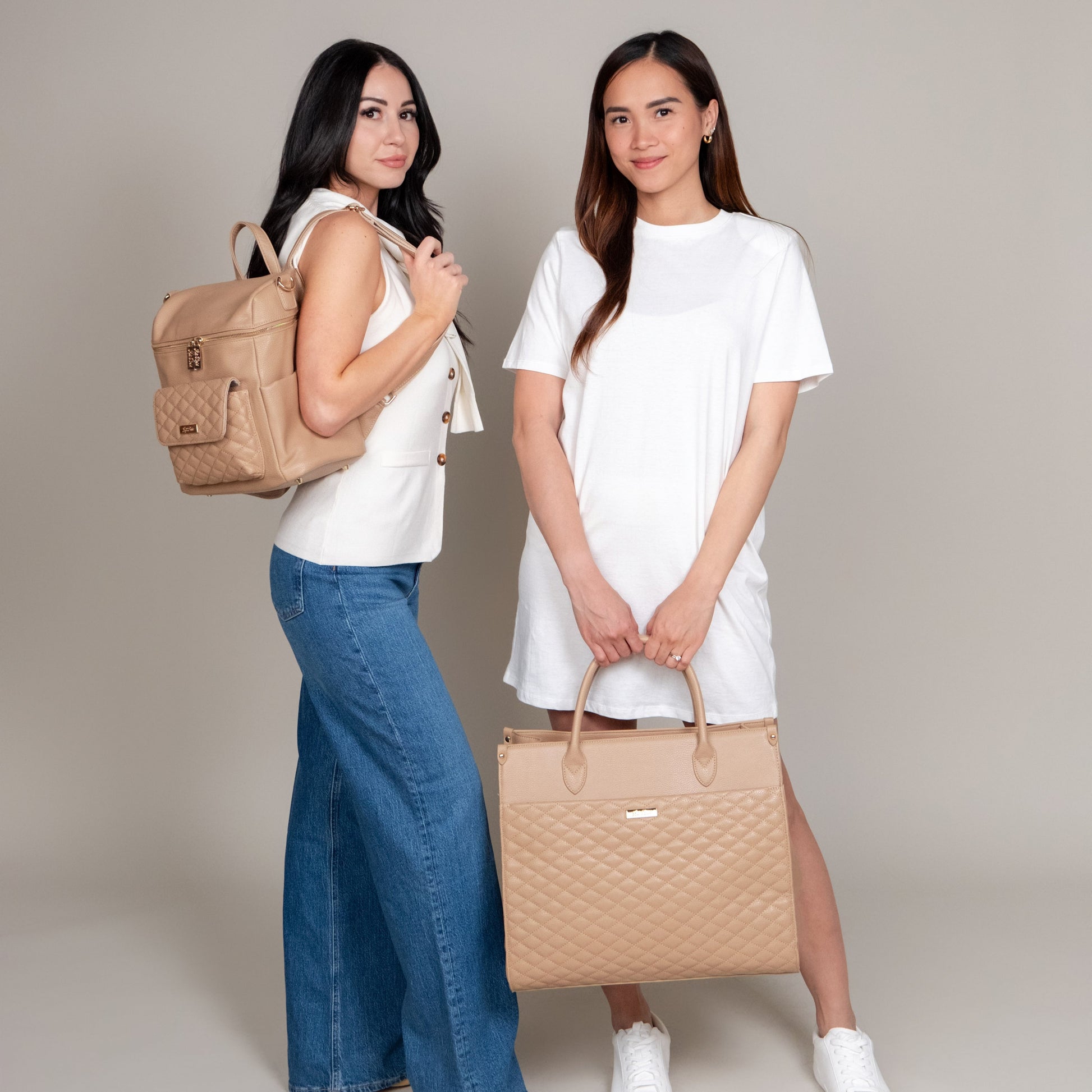 Two women holding beige handbags against a plain background