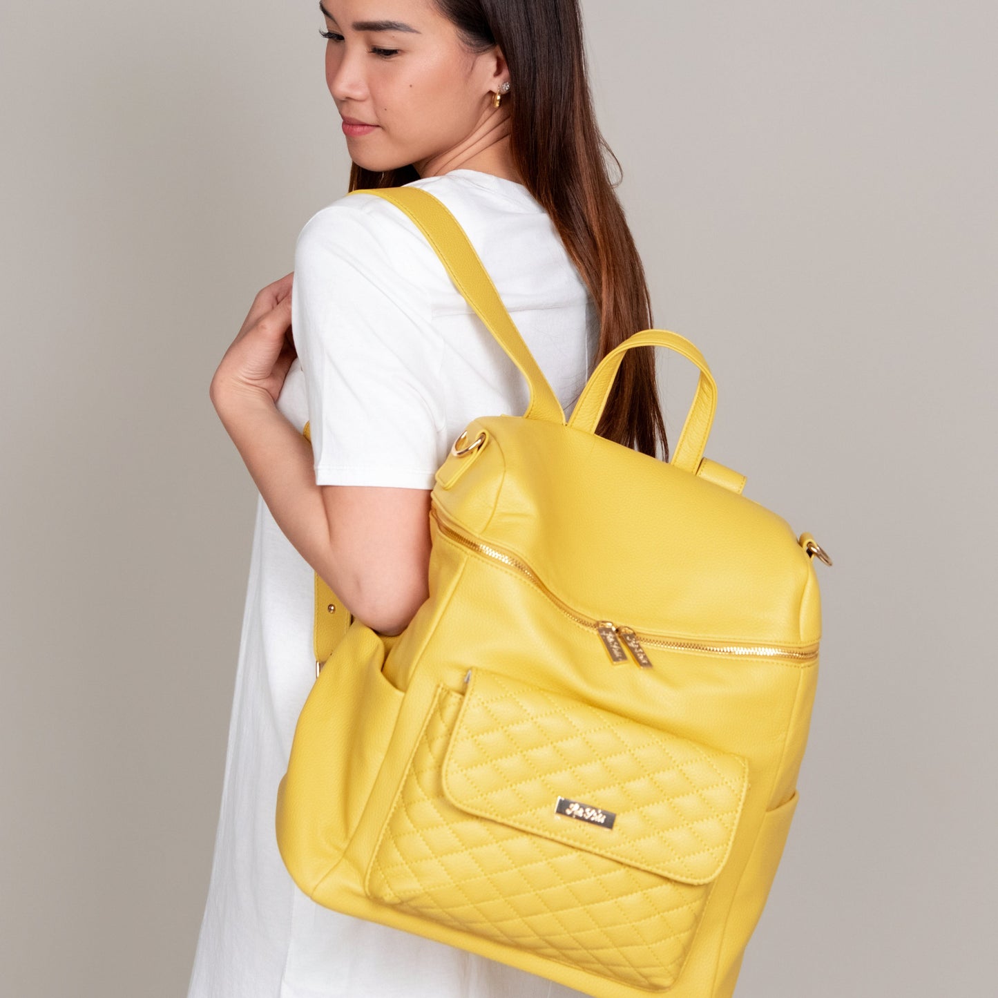 Woman wearing a yellow backpack against a neutral background