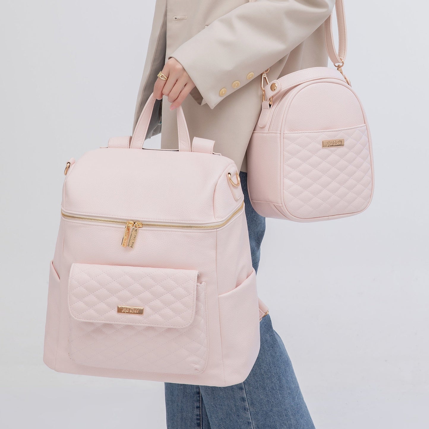 Person holding a pink backpack and quilted crossbody bag against a light gray background