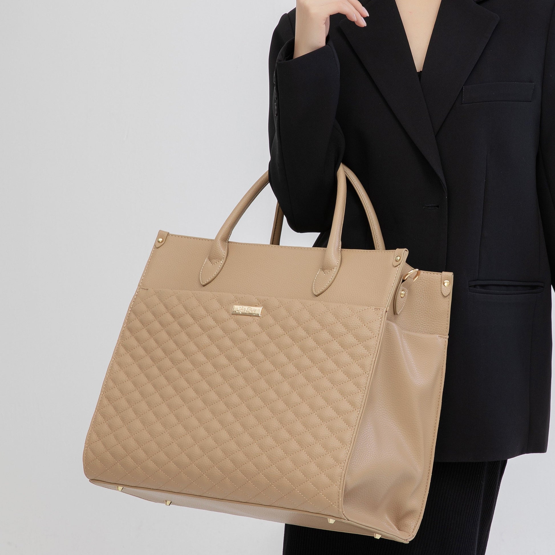 Person holding a beige quilted handbag against a plain background